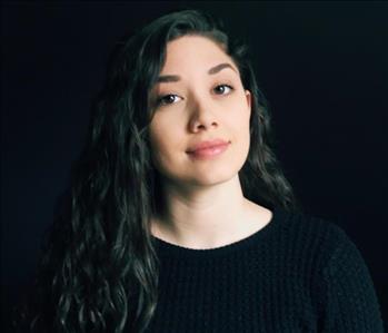 Female employee wearing black sweater with dark background 